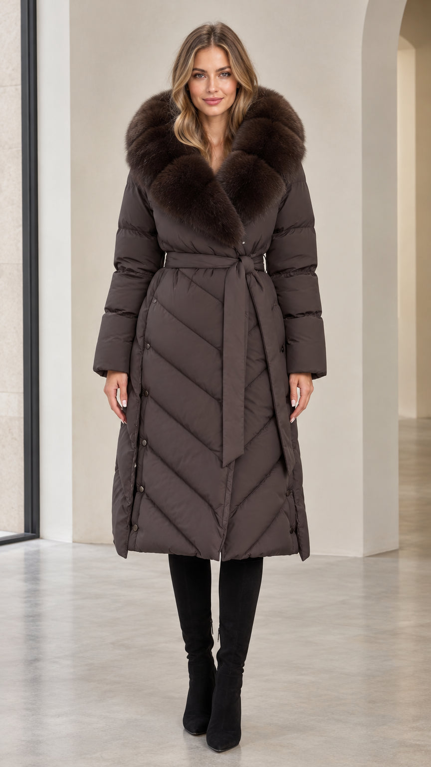 Front view of woman wearing dark brown long belted puffer coat with plush faux fur collar