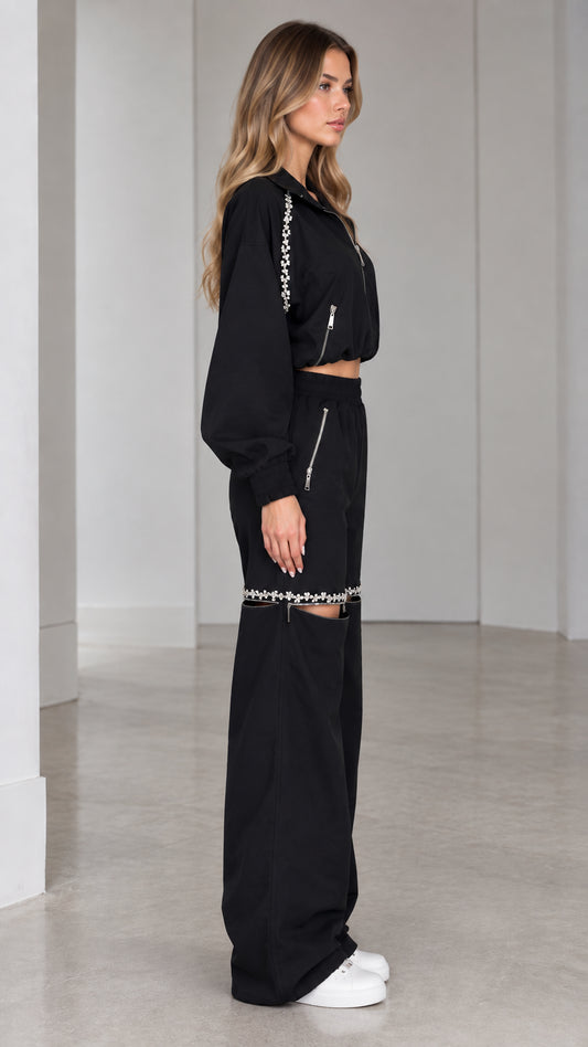 Side profile of model wearing black two-piece cropped jacket and wide-leg tracksuit set
