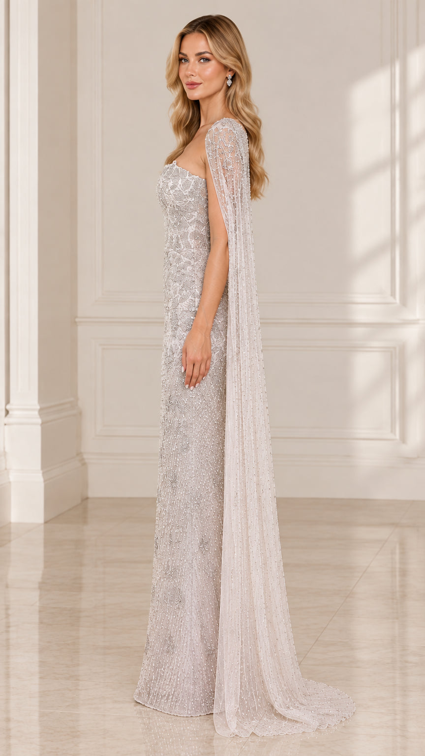 Side profile view of silver embellished strapless formal gown with flowing cape