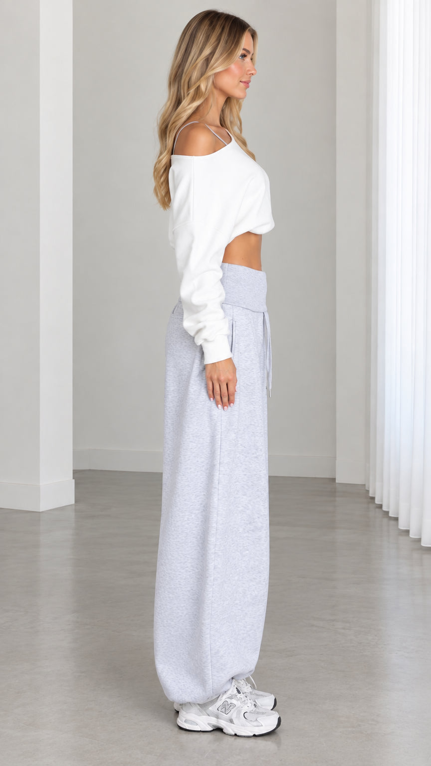 Side view of model wearing slouchy Heather Gray balloon-leg sweatpants and white crop top