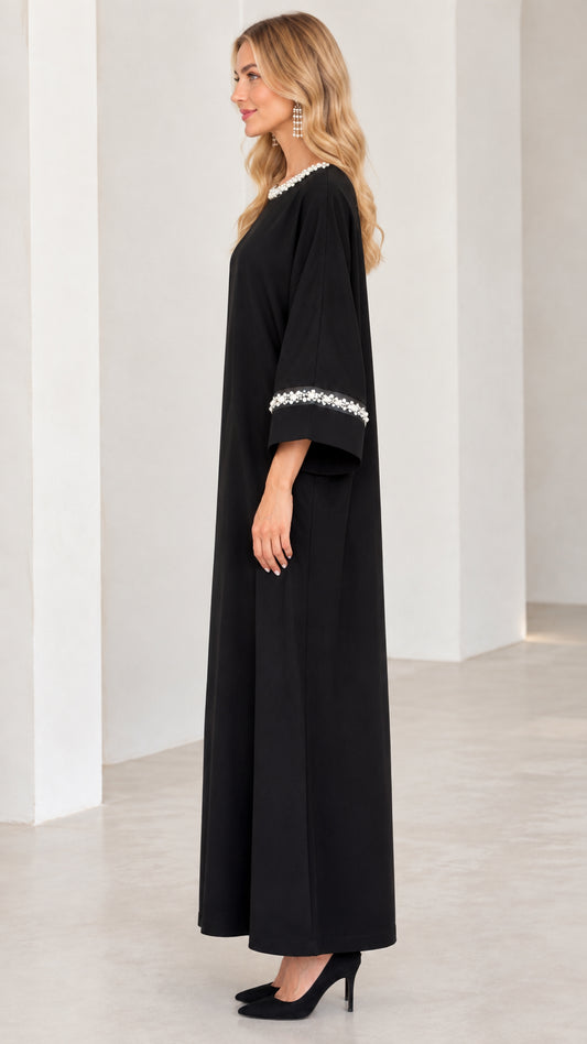 Side profile of woman in black long sleeve pearl trim abaya dress