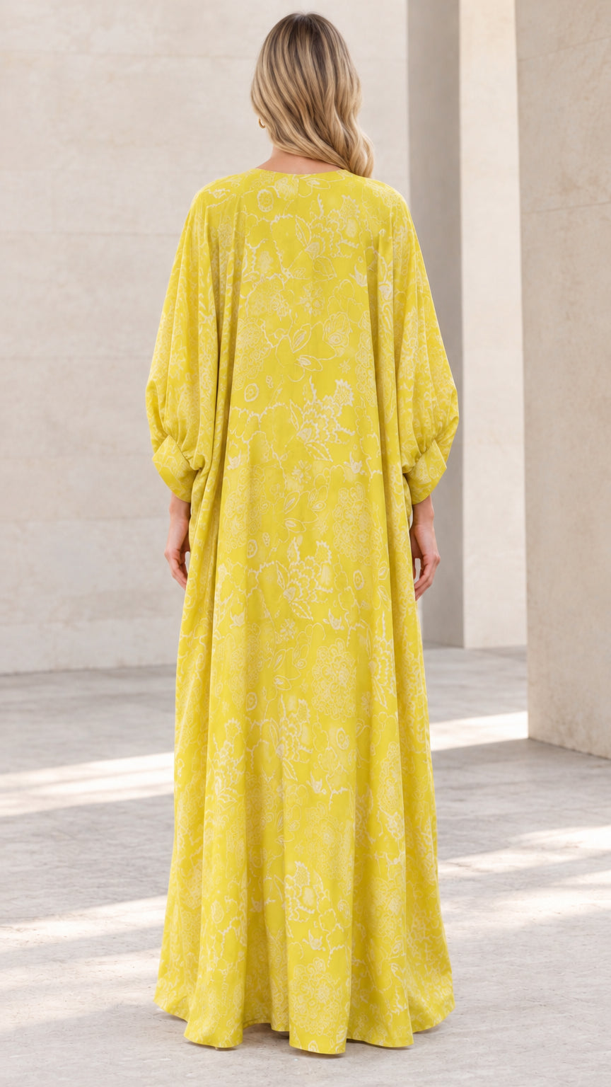 Back view of woman wearing yellow floral caftan maxi dress