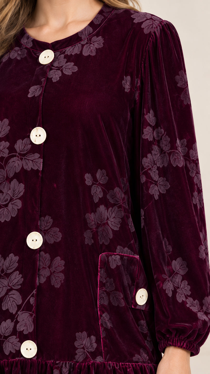 Close-up detail of burgundy floral velvet fabric, round collar, and front button accents