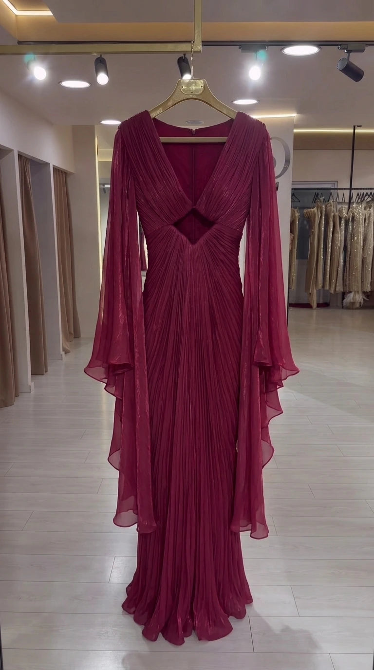 Burgundy pleated formal gown on hanger highlighting the V-neckline, cutout, and long cape sleeves
