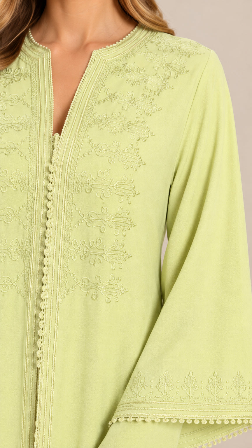 Close-up of intricate tonal embroidery on light green abaya bodice and sleeve