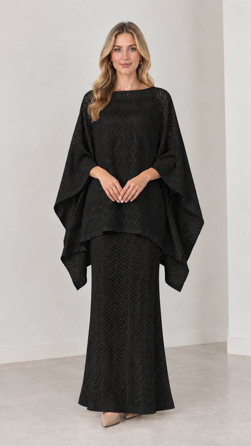 Front view of model wearing black pointelle knit cape top and maxi skirt set