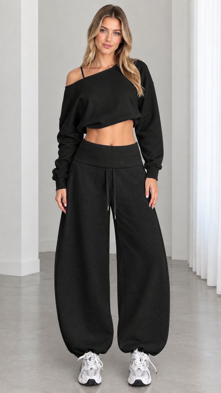 Model wearing all-black 2-piece off-the-shoulder cropped sweatshirt and balloon sweatpants set