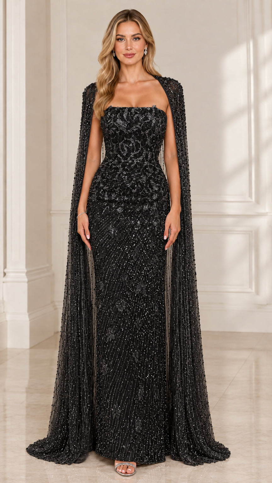 Front view of woman wearing black strapless beaded evening dress with cape overlay