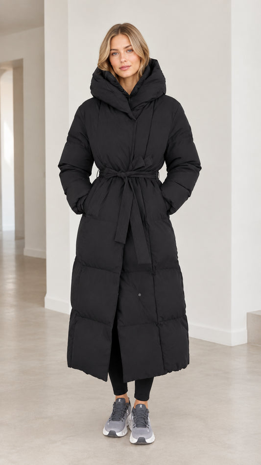 Front view of model wearing full-length black belted maxi puffer coat with hood