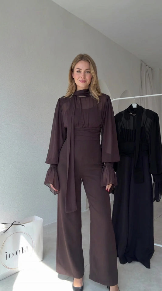 Full front view of model wearing Chocolate Brown tie-neck wide-leg jumpsuit with sheer lantern sleeves