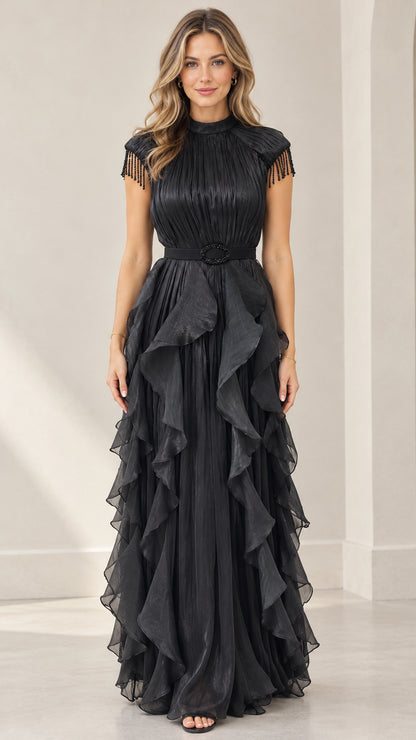 Front full-length view of woman wearing black pleated tiered ruffle evening maxi dress with beaded fringe cap sleeves