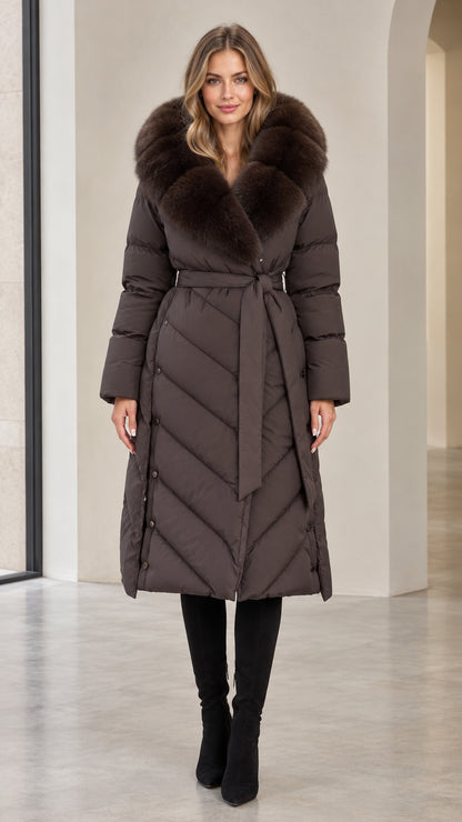 Front view of woman wearing dark brown long belted puffer coat with plush faux fur collar