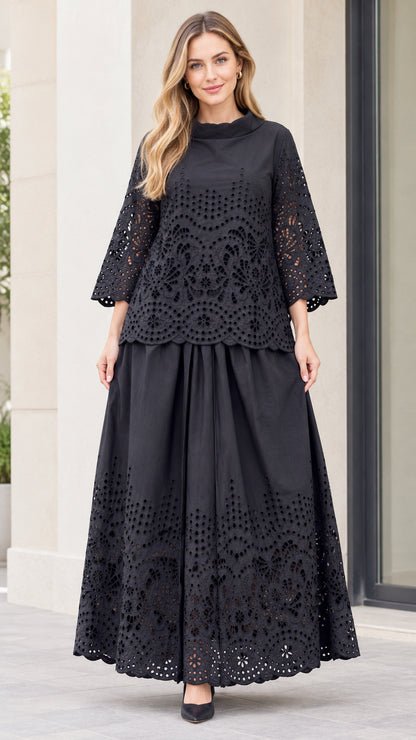Front full-length view of woman wearing black eyelet embroidered mock neck top and maxi skirt set