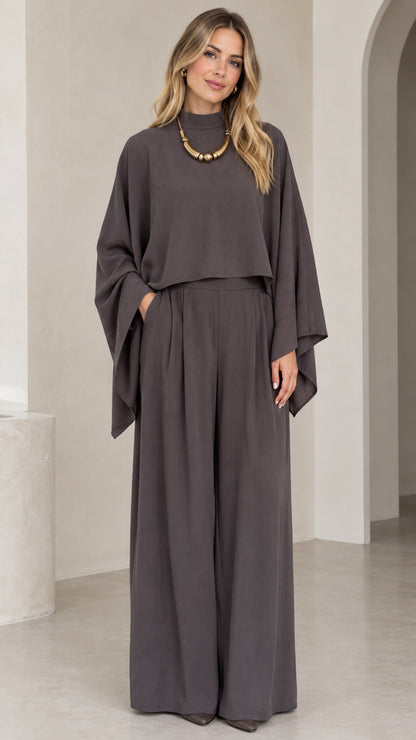 Front full-length view of woman wearing charcoal grey mock neck cape top and pleated wide leg pants set