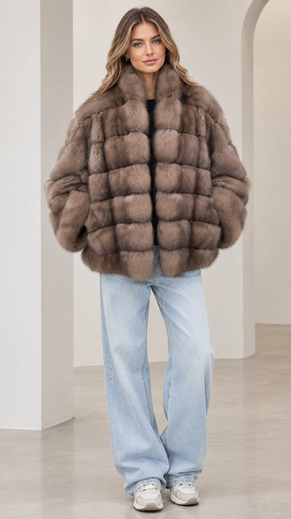 Front view of model wearing a taupe paneled faux fur jacket with light wash jeans