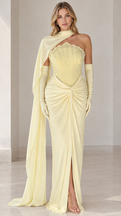 Front view of model wearing light yellow embellished corset evening gown with cape scarf and gloves