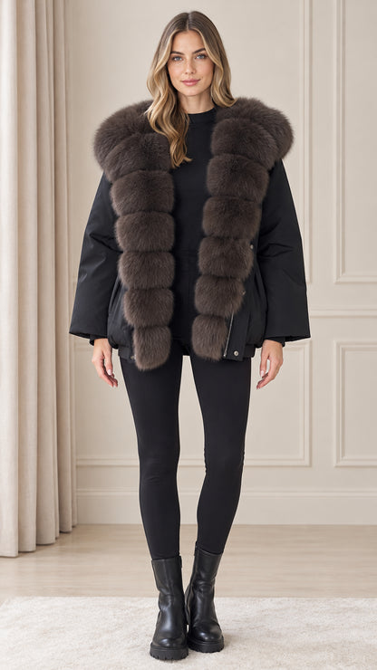 Front view of model wearing black plush hooded winter parka coat with black leggings and boots