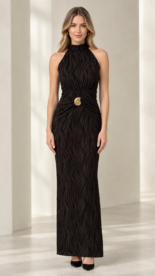 Front view of woman wearing black textured halter maxi dress with gold waist brooch
