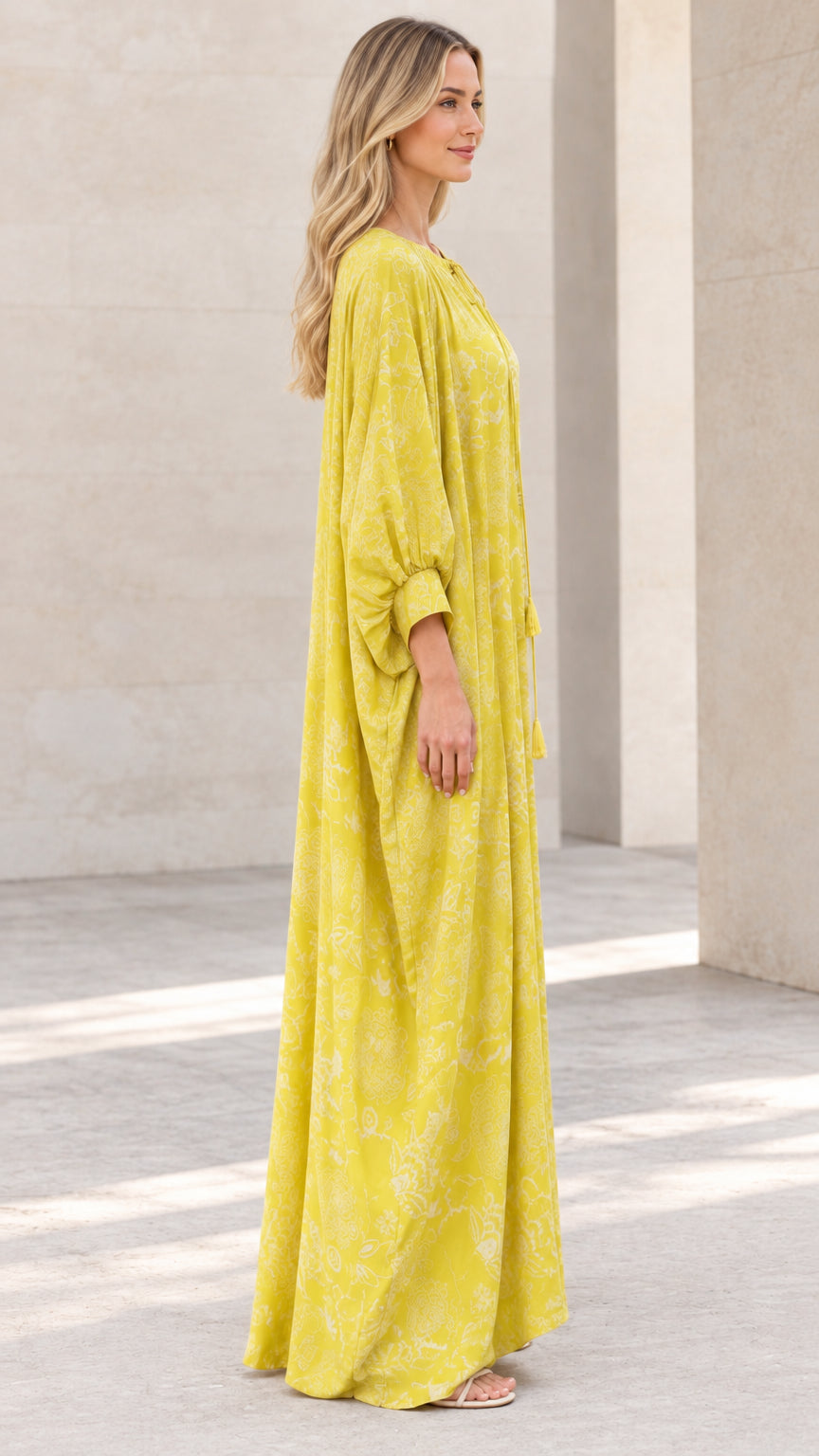 Side profile view of woman in flowing yellow floral caftan dress