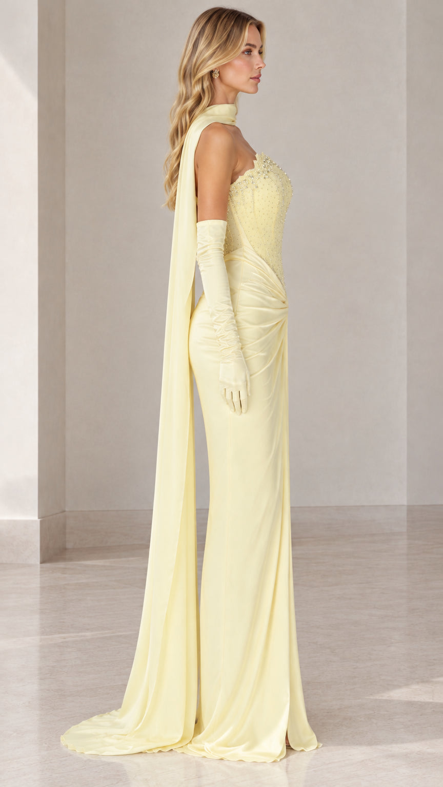 Side profile of model in light yellow formal gown with draped cape detail