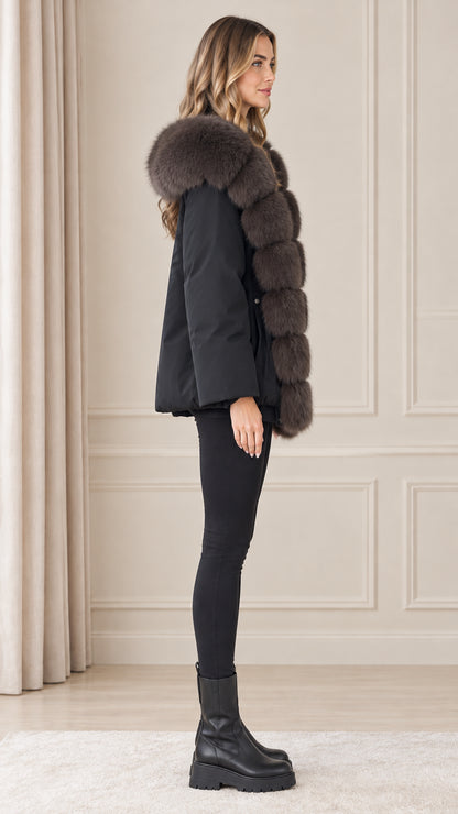 Side profile of model wearing black hooded parka jacket with plush trim