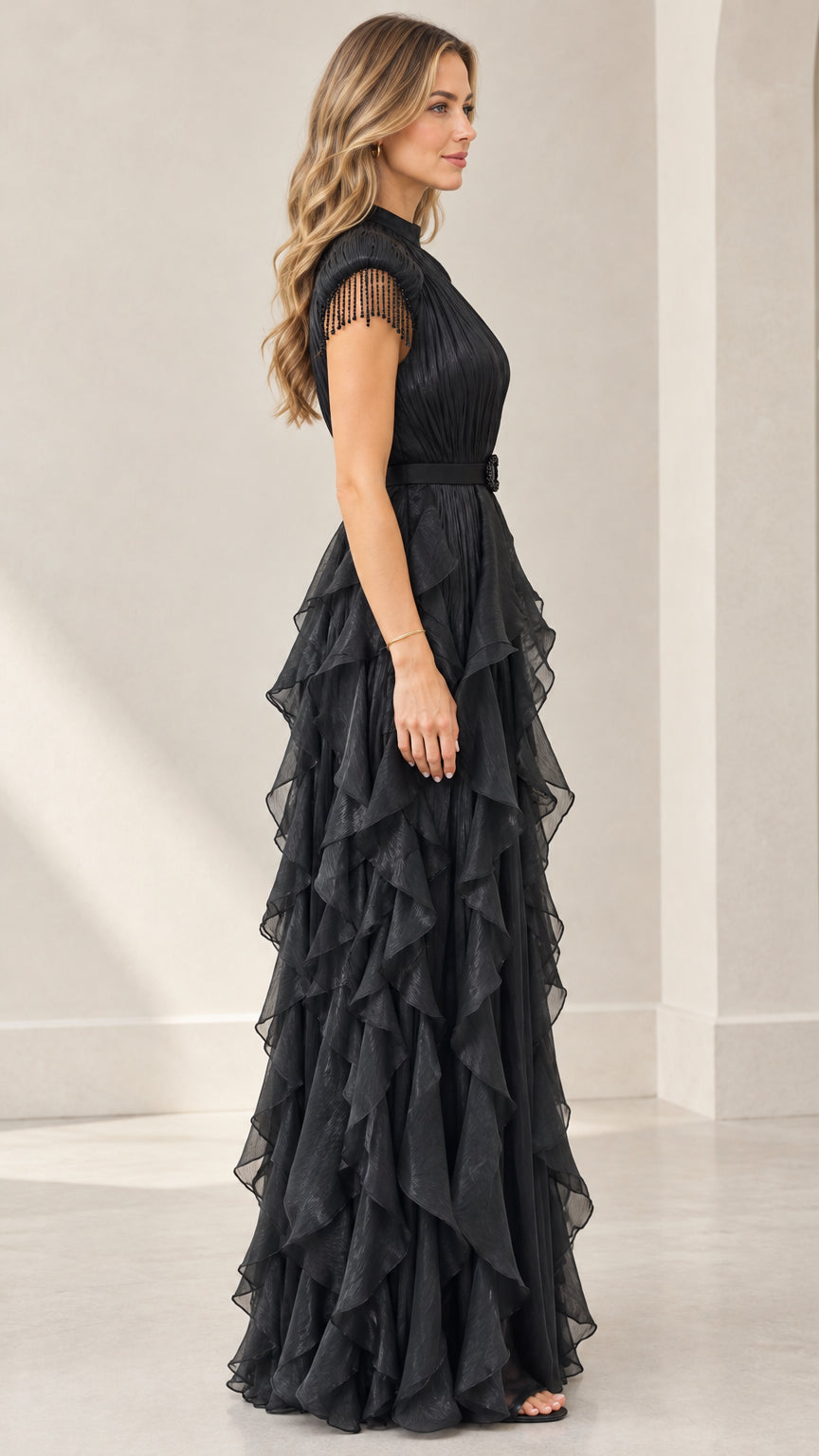 Side profile view of woman wearing black tiered ruffle pleated formal gown