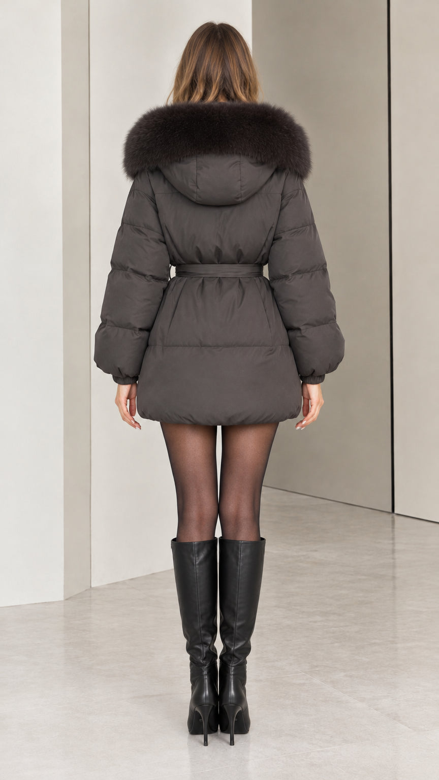 Back view of dark grey belted quilted puffer jacket with plush hood