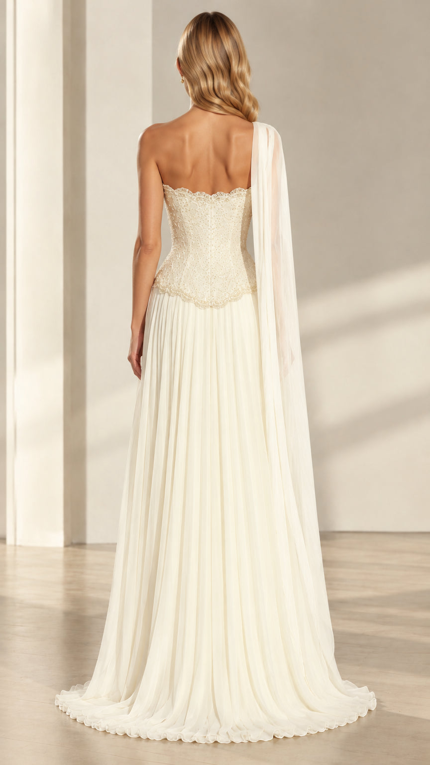 Back view of ivory strapless bodice and flowing one-shoulder cape dress
