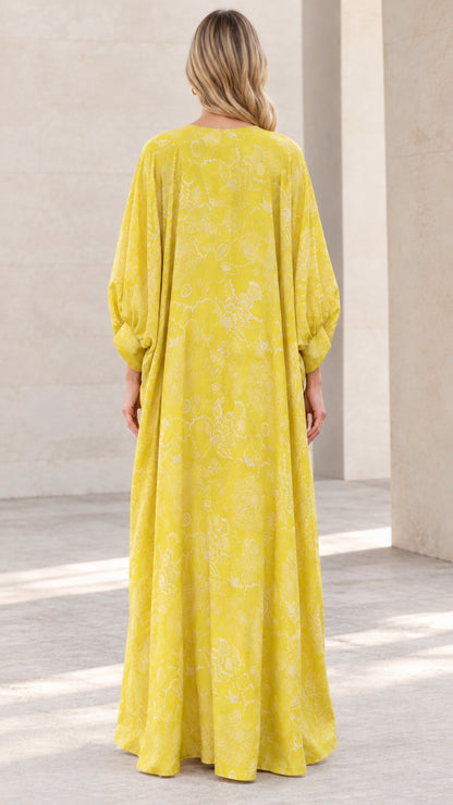 Back view of woman wearing yellow floral caftan maxi dress