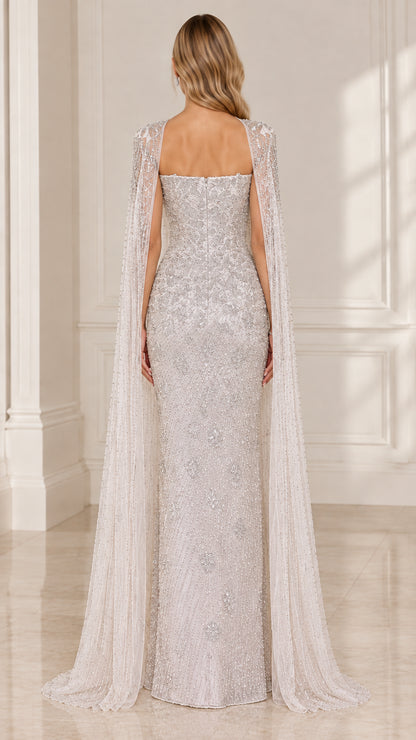 Back view of silver beaded maxi gown showing straight backline and trailing sheer cape