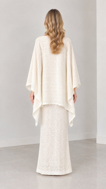 Back view of model wearing cream draped cape knit two-piece set
