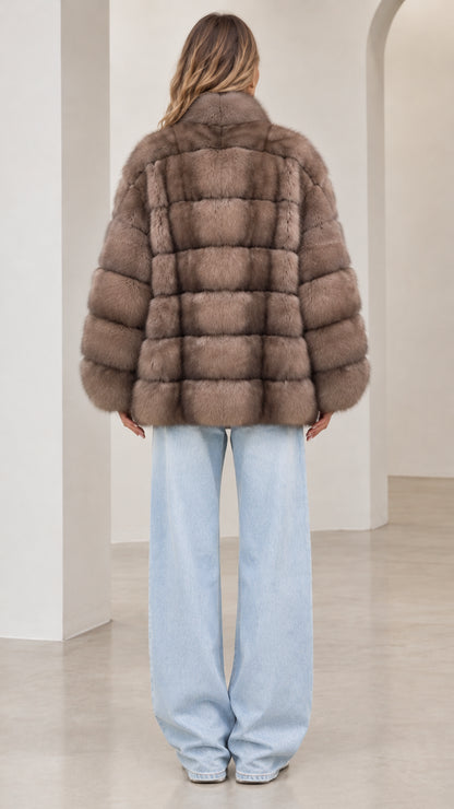 Back view of model wearing the taupe paneled faux fur jacket