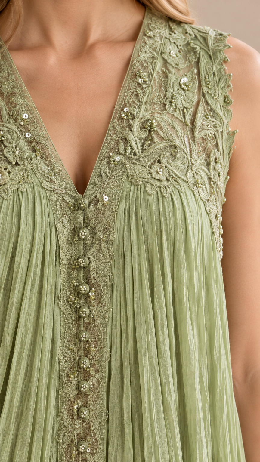 Close up of sage green lace embroidered V-neck bodice with beading and pleated overlay