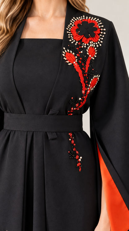 Close-up detail of red floral beaded embroidery and neckline on black dress