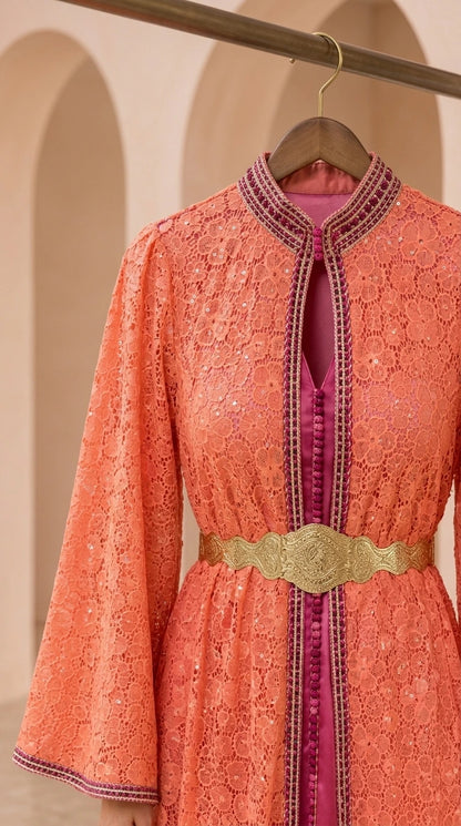 Close-up detail of coral lace fabric, neckline trim, and metallic waist belt