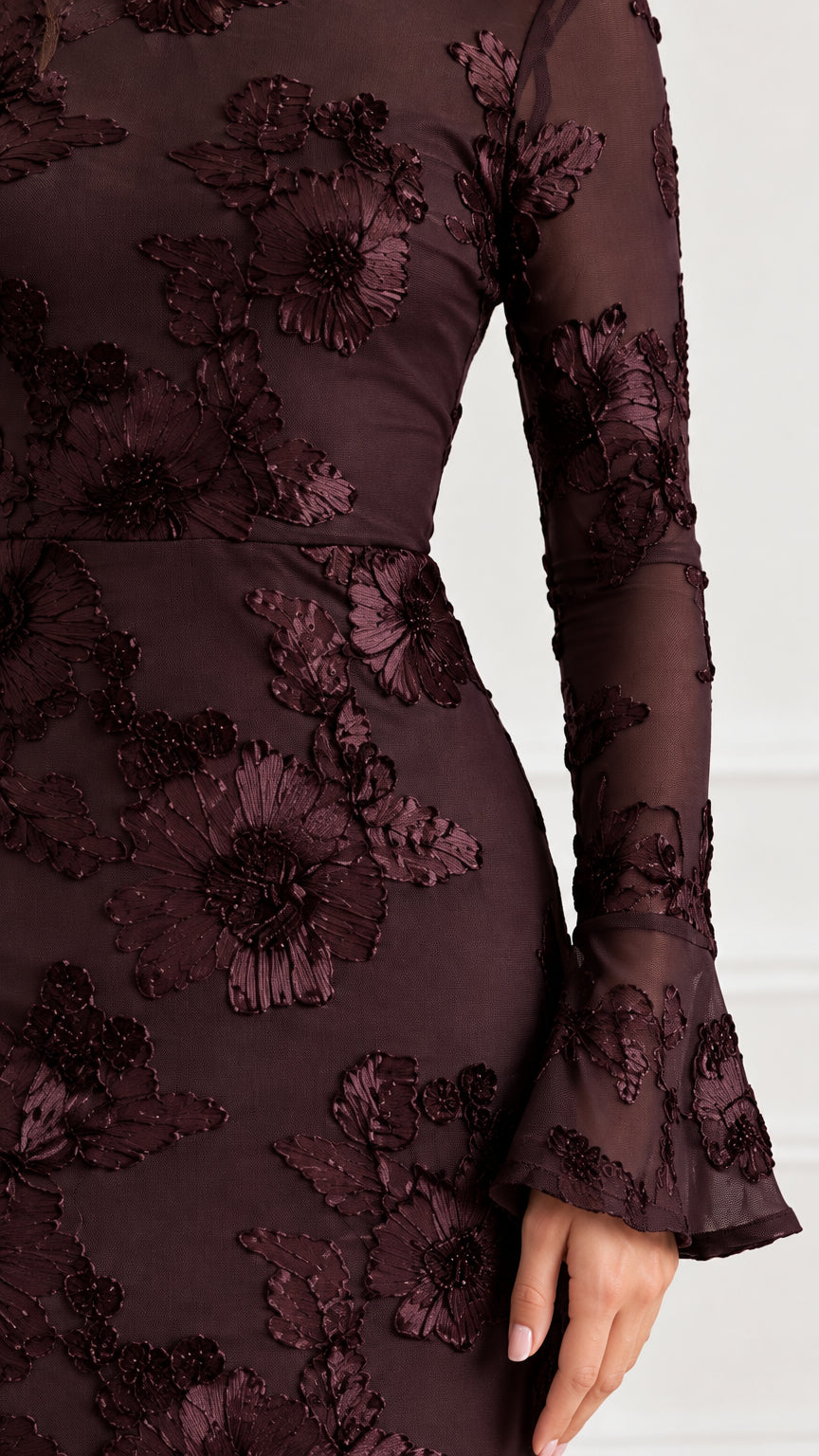 Close-up detail of textured floral appliqué embroidery on burgundy mesh fabric