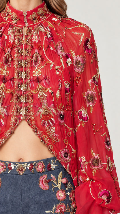 Close-up detail of high collar, intricate floral embroidery, and embellishments on red cape