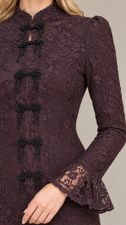 Close-up detail of beaded bow frog closures on textured floral lace bodice