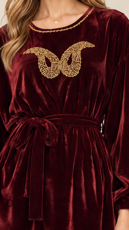 Close-up detail of golden butterfly embellishment and neckline on burgundy velvet top