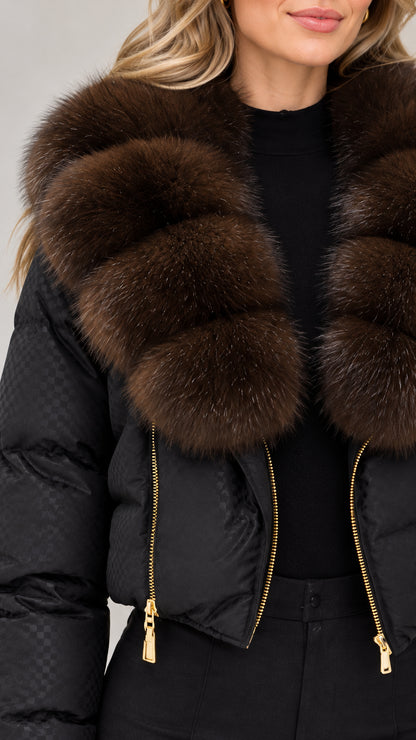 Close-up detail of textured quilted shell, gold zipper, and plush faux fur collar on black jacket