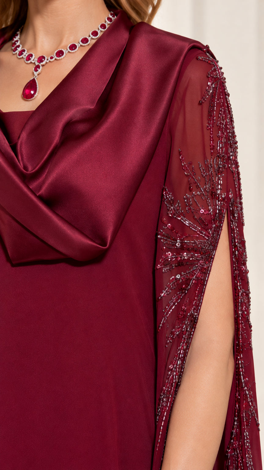 Close-up detail of burgundy satin cowl neckline and beaded sheer sleeve