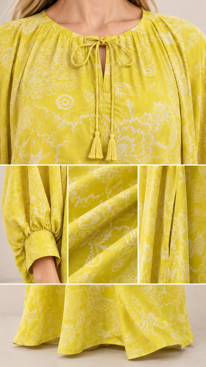 Close-up details of neckline tassel tie, gathered sleeve cuff, fabric drape, and hem