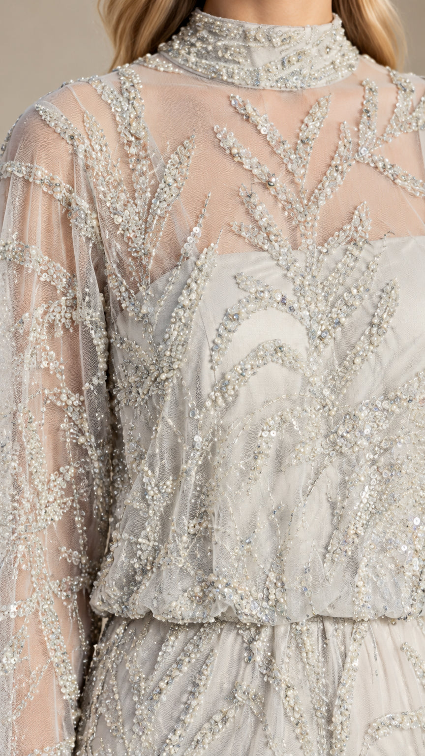 Close-up detail of sheer mock neckline and botanical beadwork on silver evening gown
