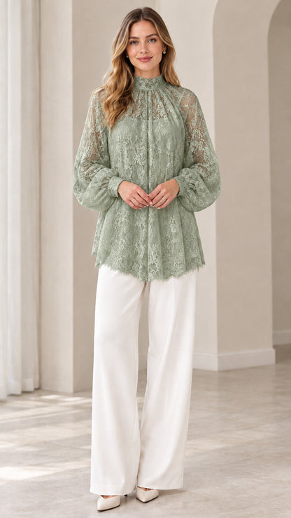 Full look of woman wearing sage green high neck floral lace blouse with white wide leg pants