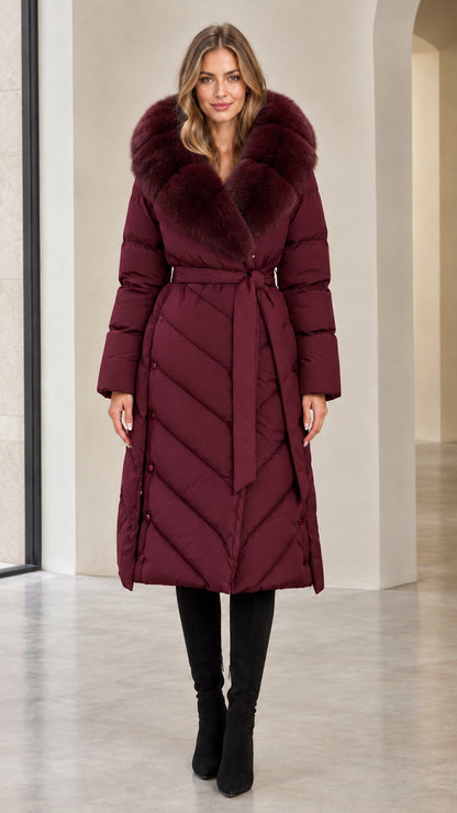 Full-length view of woman in deep burgundy red belted long puffer coat with matching fur trim