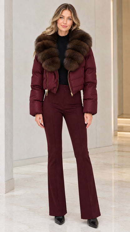 Model wearing burgundy red cropped puffer jacket with brown faux fur collar and wine red flare trousers