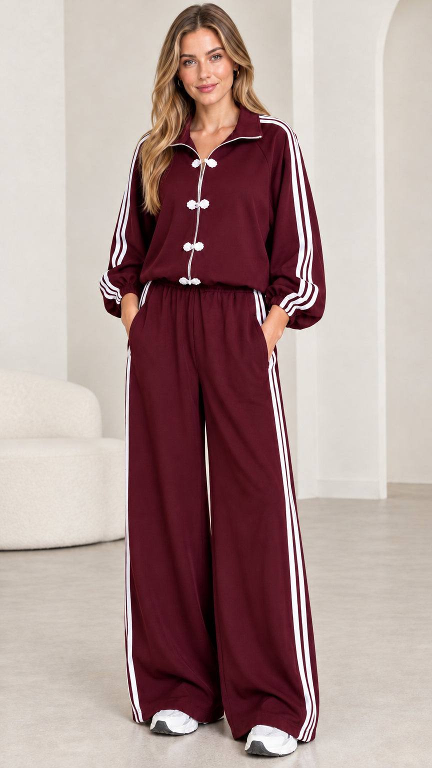 Model wearing burgundy red two-piece tracksuit set with side stripes